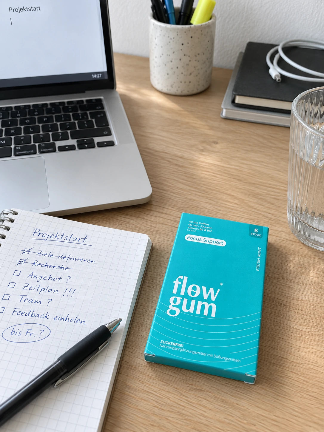 Schreibtisch am Nachmittag mit Laptop, To-do-Liste, Wasserglas und einer Packung Flow Gum